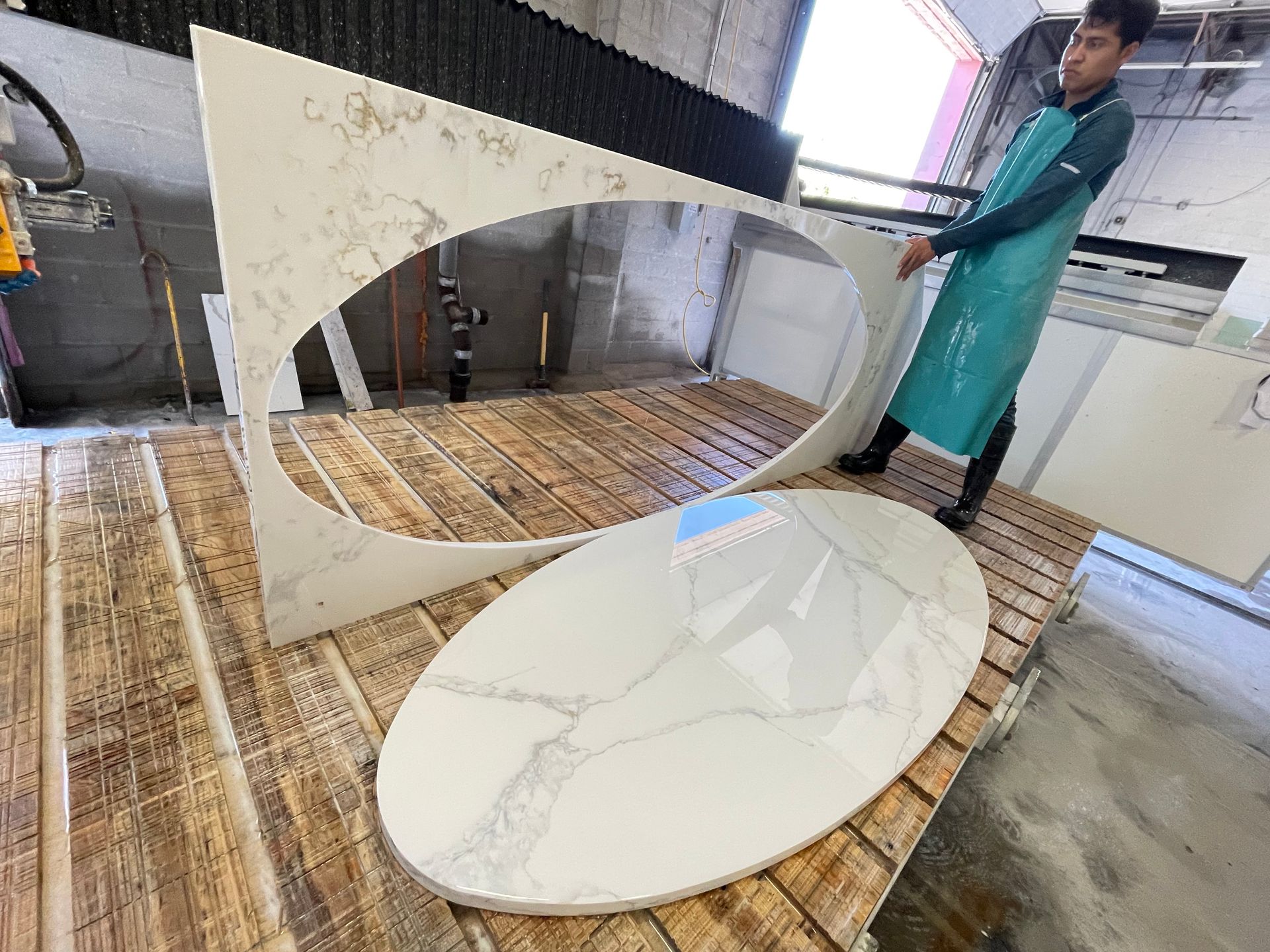 A man is standing next to a large oval piece of marble.