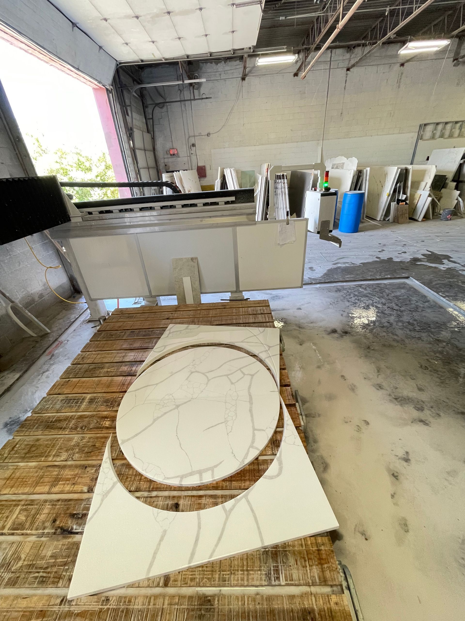 A circular piece of marble is sitting on top of a wooden table in a warehouse.