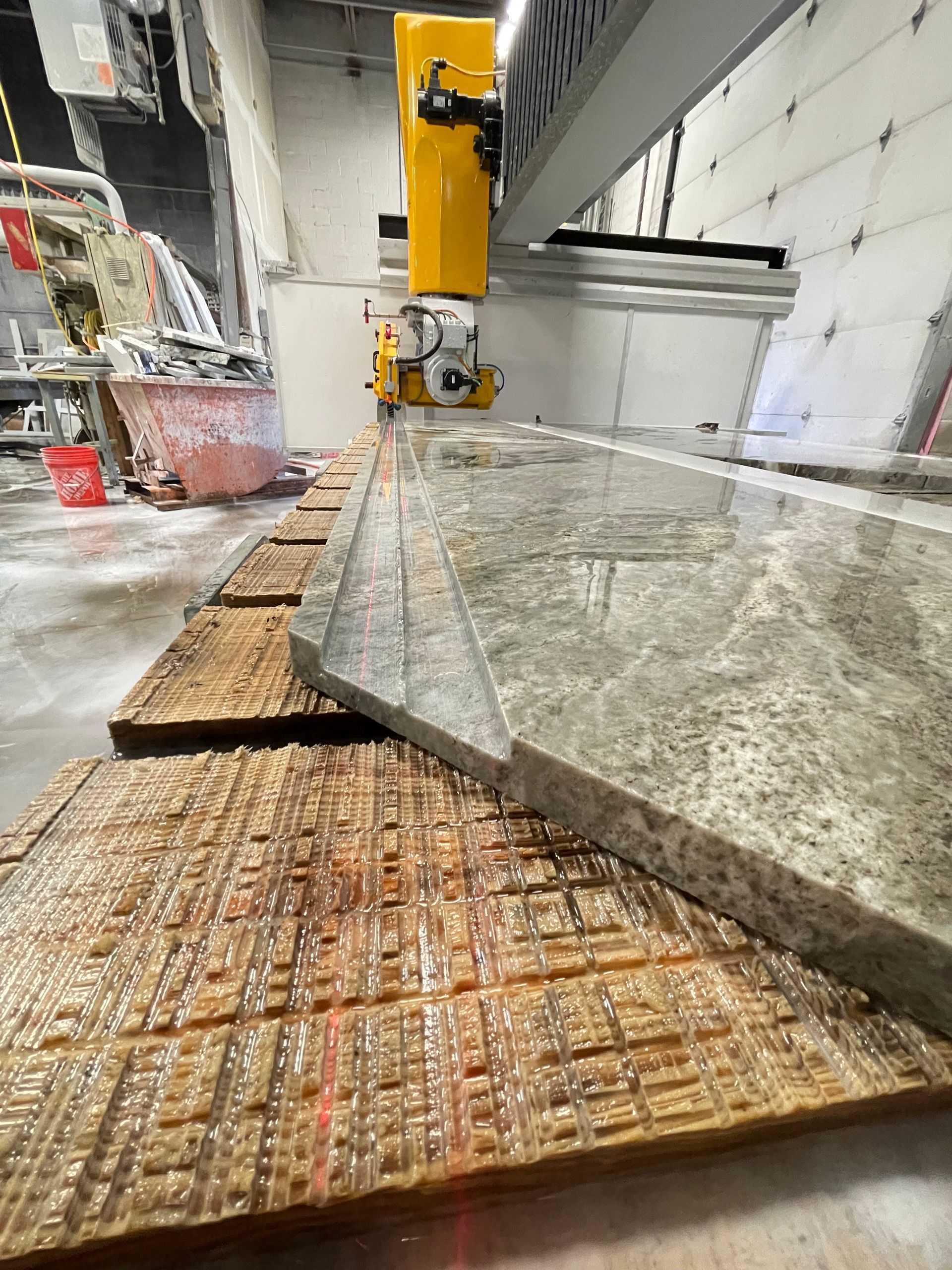 A machine is cutting a piece of granite on a table.