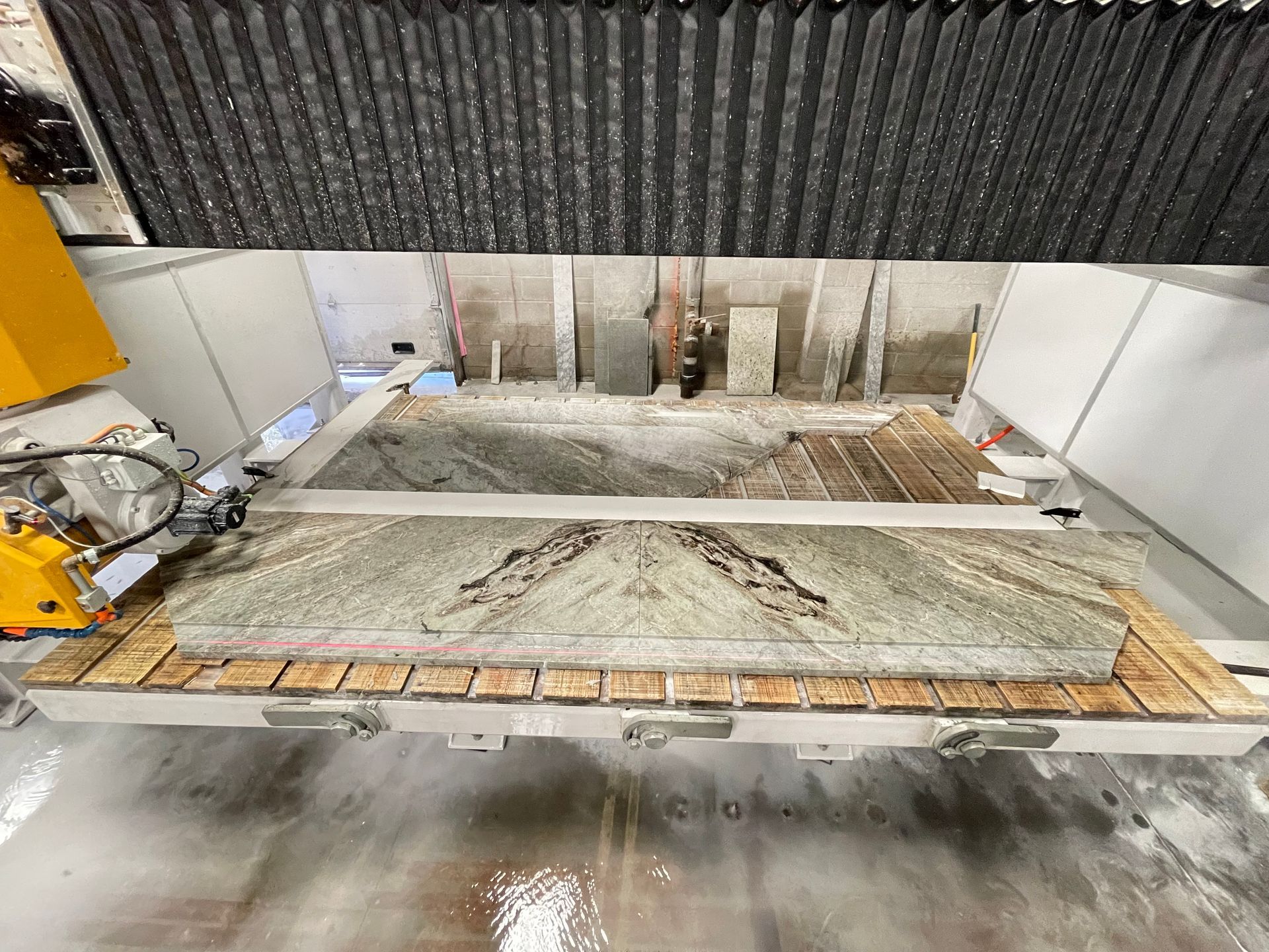 A machine is cutting a piece of granite on a table.