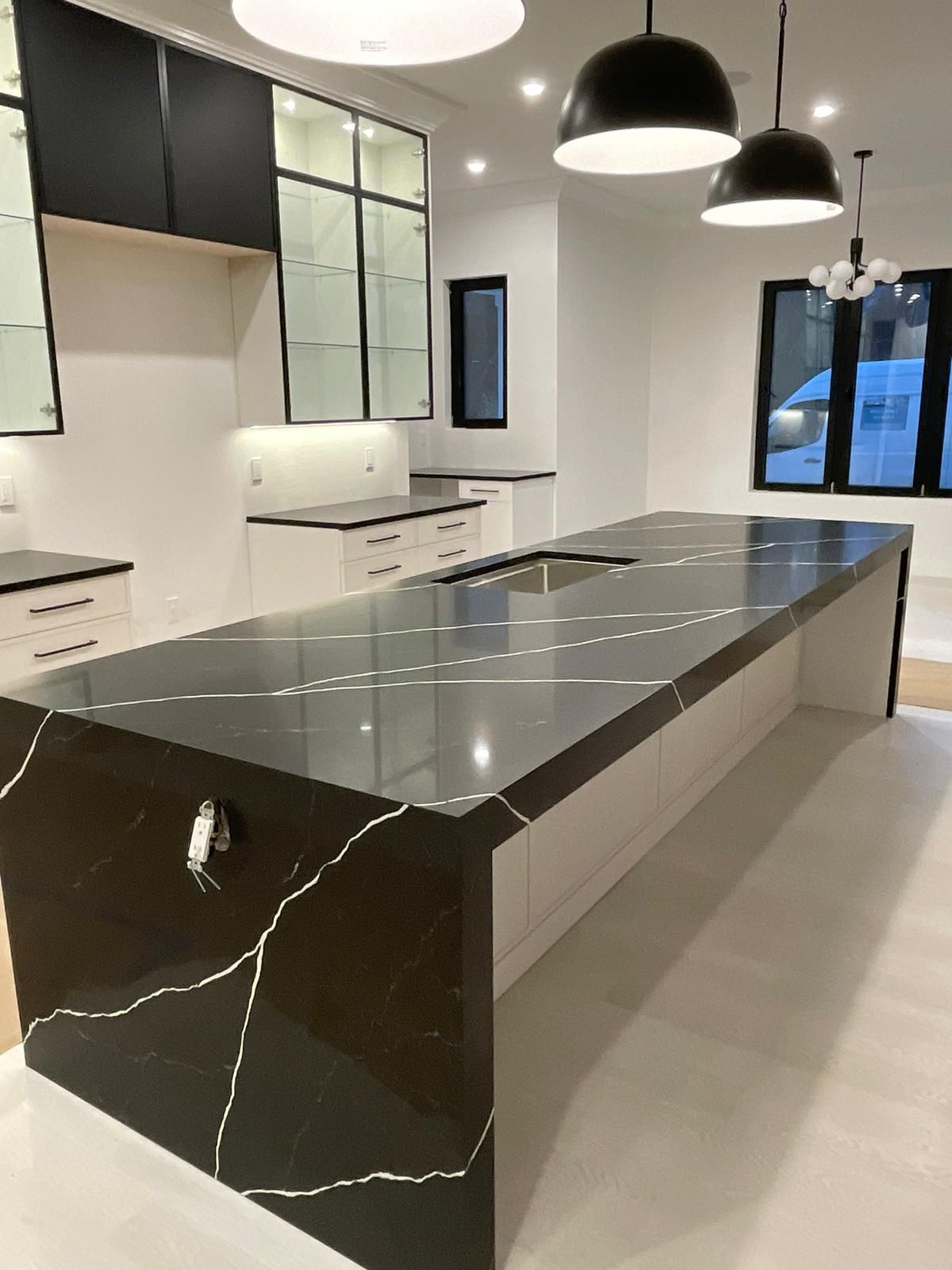 A kitchen with a long black counter top and white cabinets.