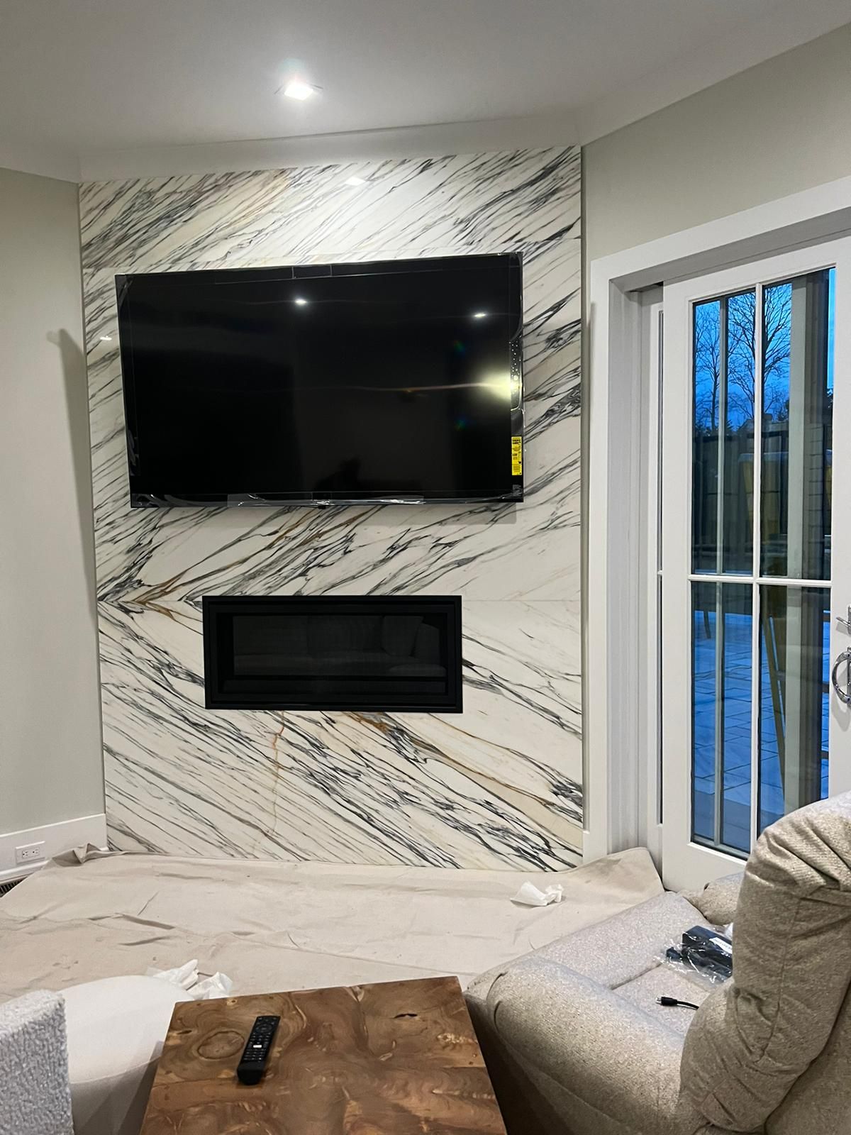 A living room with a fireplace and a flat screen TV on the wall.