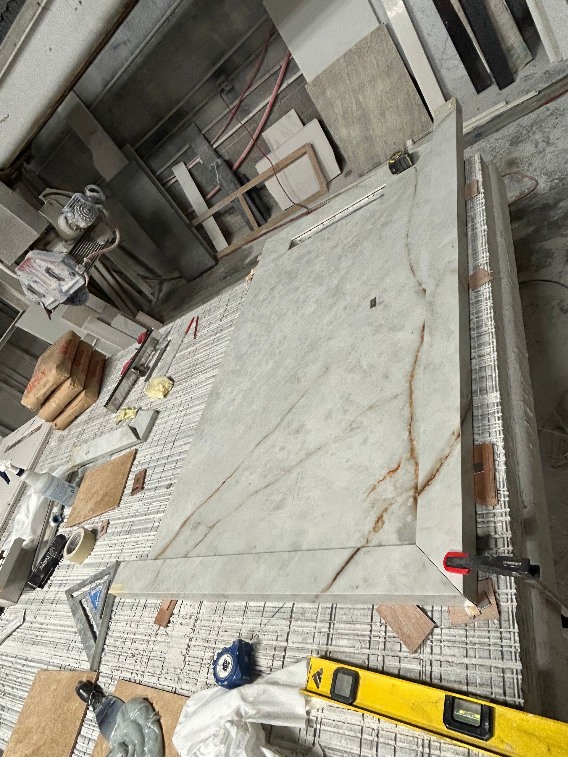 A yellow level is sitting on top of a marble countertop.