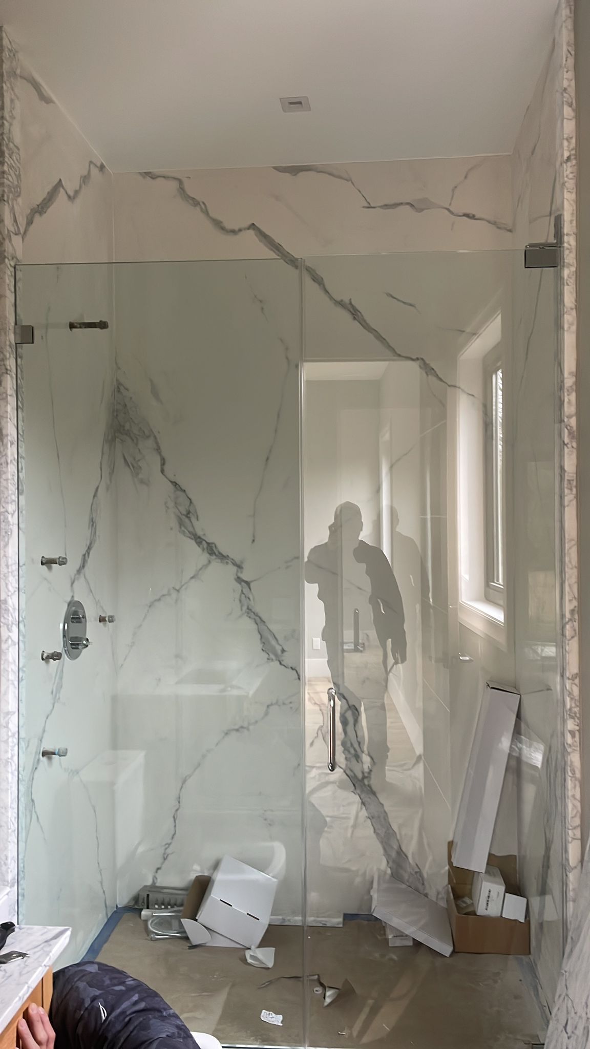 A bathroom with a marble wall and a glass shower door.
