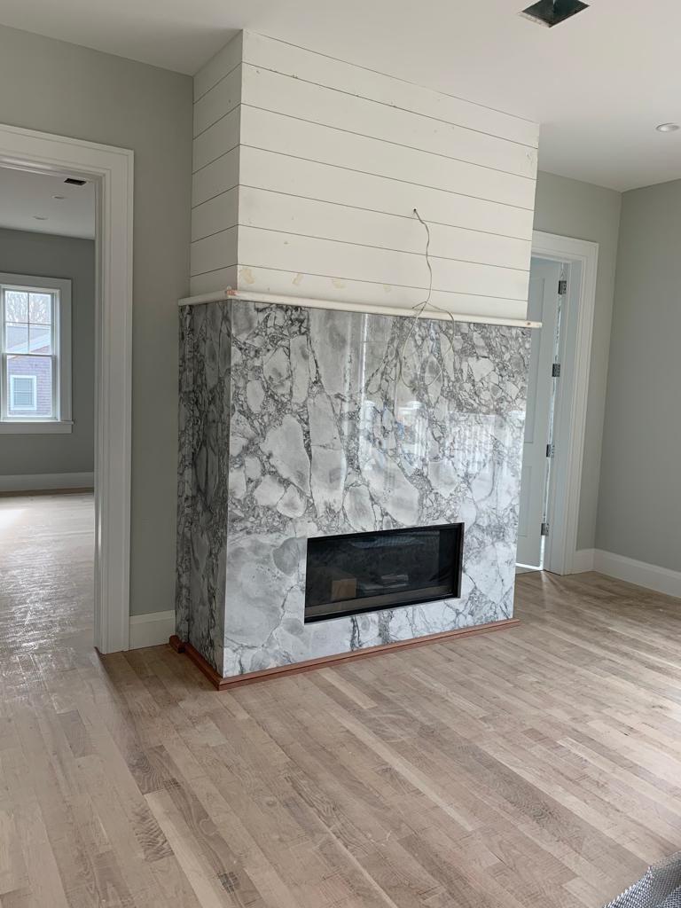 A living room with a marble fireplace and hardwood floors.