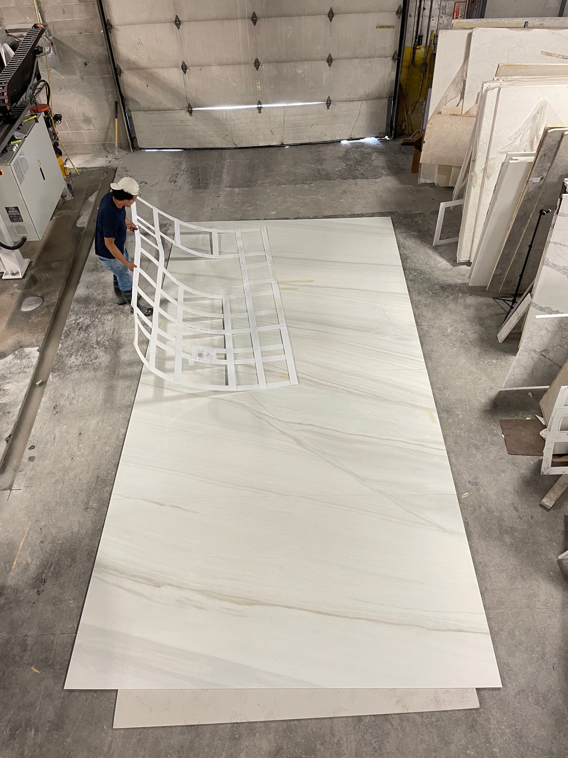 A man is standing next to a large white marble slab in a warehouse.