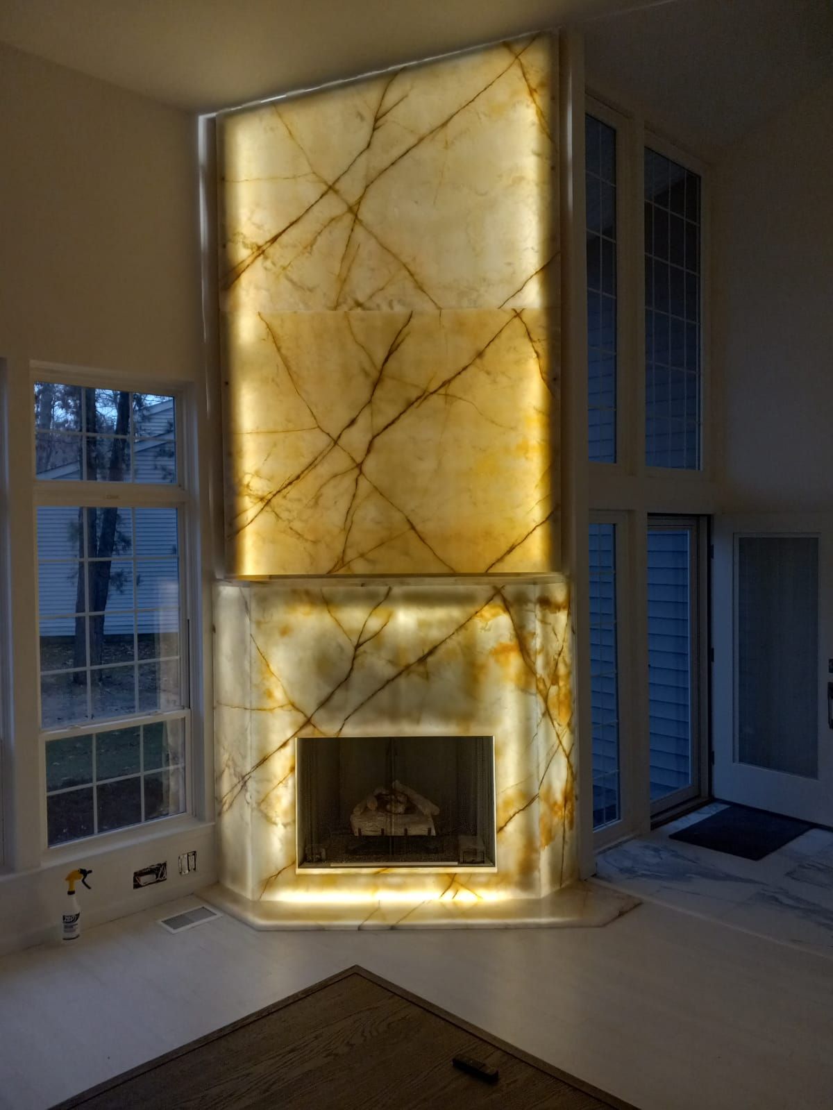 A living room with a fireplace and a marble wall.