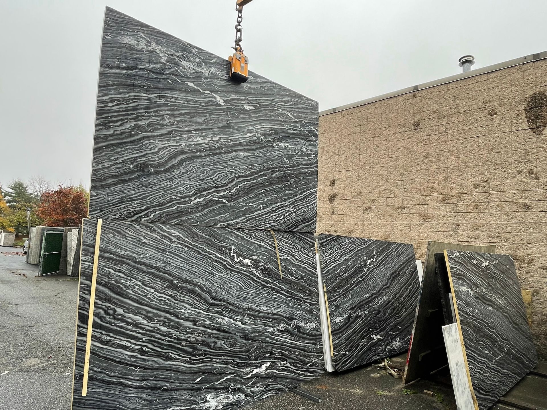 A large piece of black granite is being lifted by a crane.