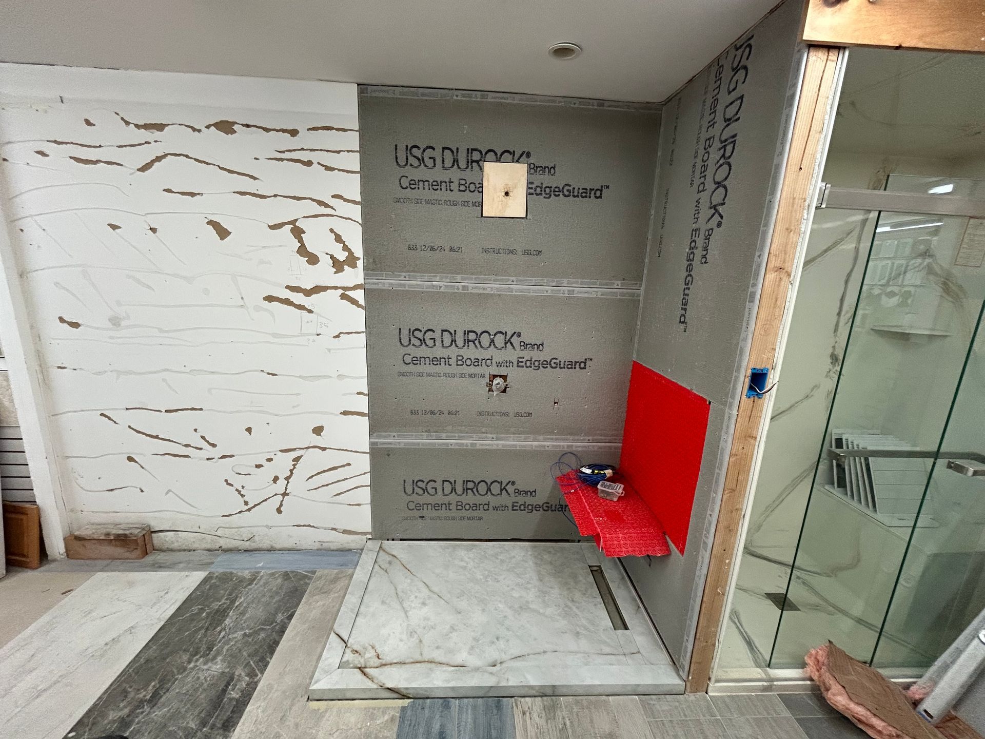 A bathroom with a red sink and a gray wall.