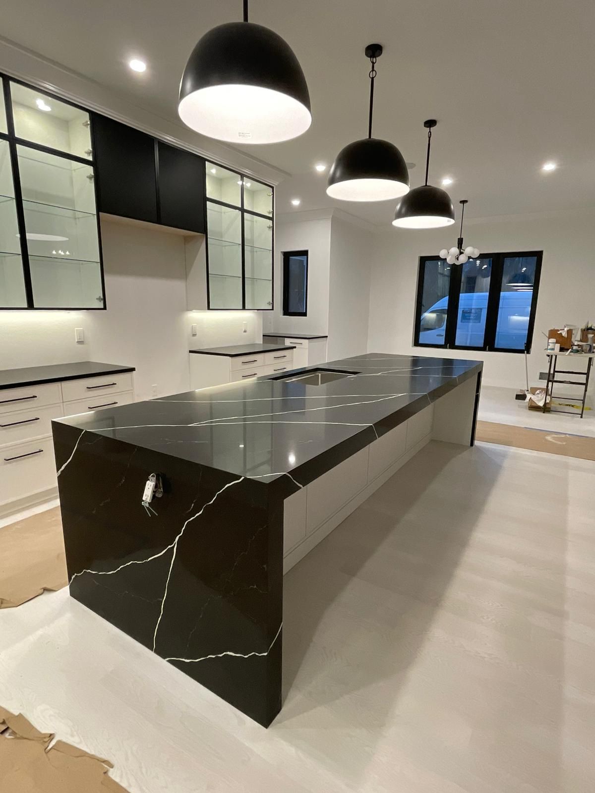 A kitchen with a large black counter top and white cabinets.