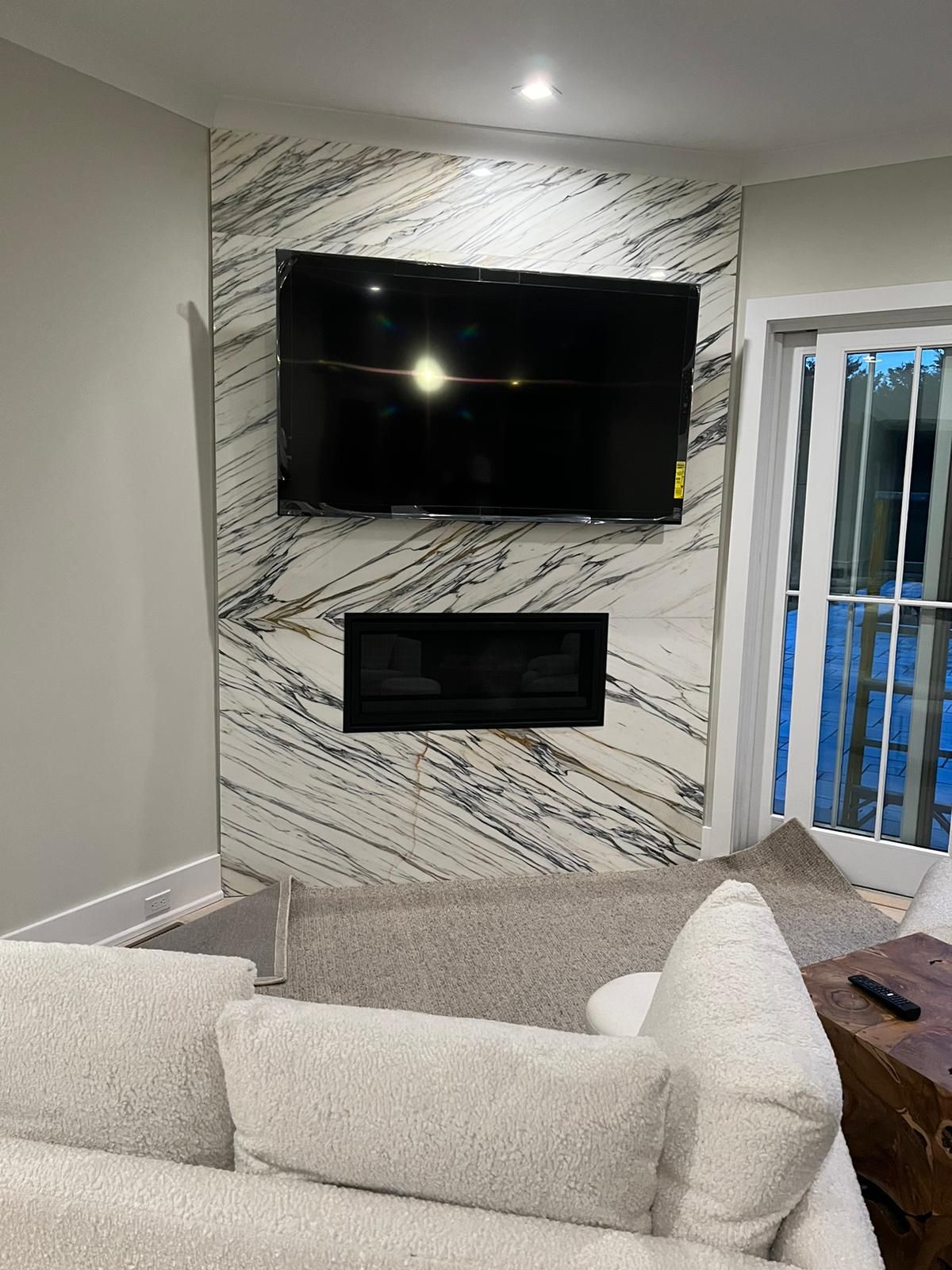 A living room with a fireplace and a flat screen tv on the wall.