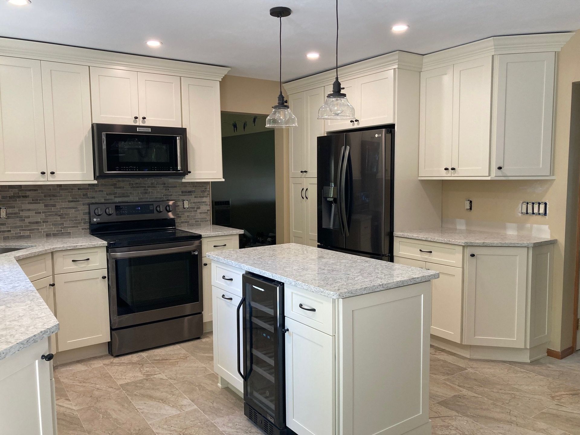 A kitchen with white cabinets , stainless steel appliances , granite counter tops and a large island.