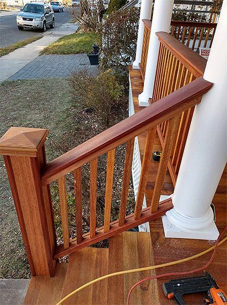 A wooden railing is being installed on a porch