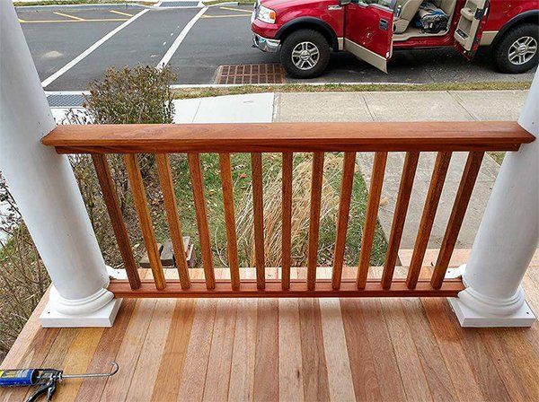 A red truck is parked next to a wooden railing on a porch