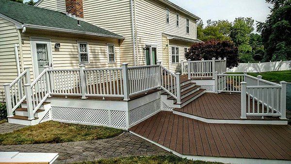 A large deck with stairs and a white railing in front of a house