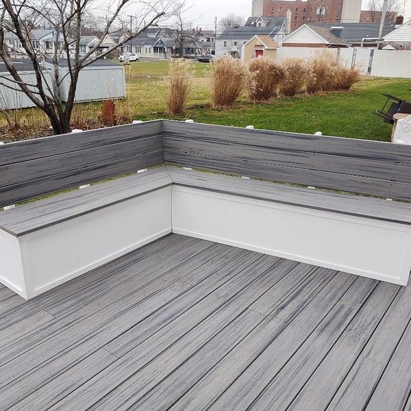 A wooden deck with a bench and a planter on it