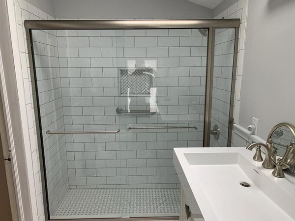 A bathroom with a sliding glass shower door and a sink