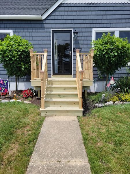 A blue house with a wooden deck and stairs in front of it