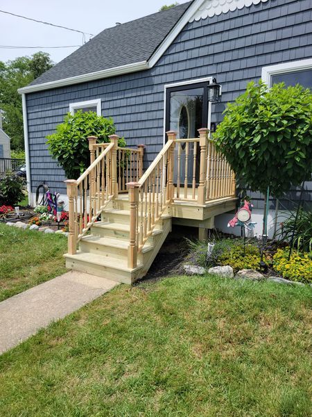 A blue house with a wooden deck and stairs in front of it
