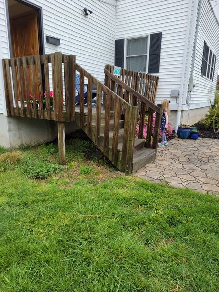 A wooden deck with stairs leading up to it in front of a house