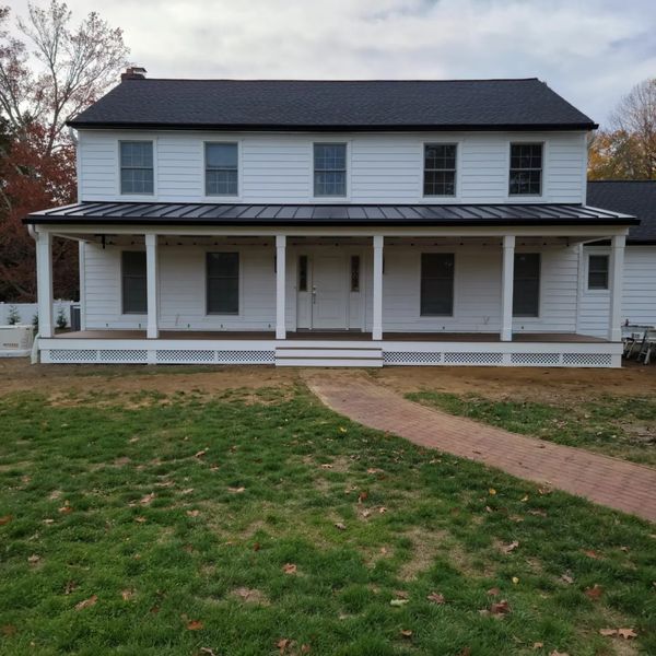 A large white house with a black roof and a large porch
