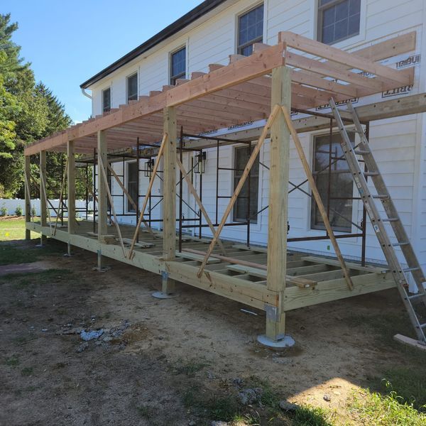 A wooden deck is being built in front of a white house