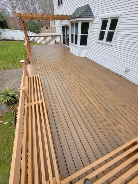 A large wooden deck with a pergola on top of it in front of a house