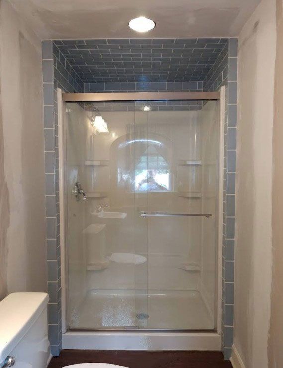 Shower stall with light blue tile accents; white walls.