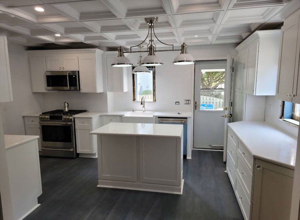 White kitchen with island, stainless steel appliances, and coffered ceiling.