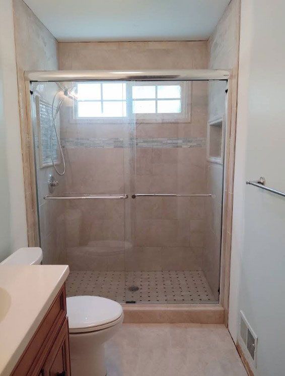 Shower stall with glass doors, toilet, and vanity in a bathroom.