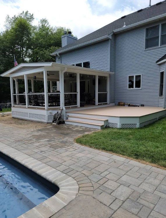 A two-story blue house with a screened porch and deck overlooking a pool.