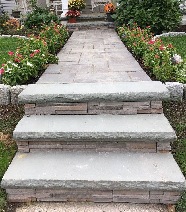 Stone steps leading to a walkway lined with flowers; autumn foliage.