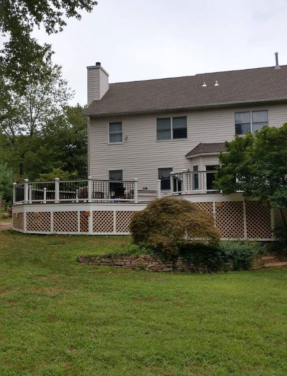Backyard view of a two-story house with a large deck featuring lattice work.