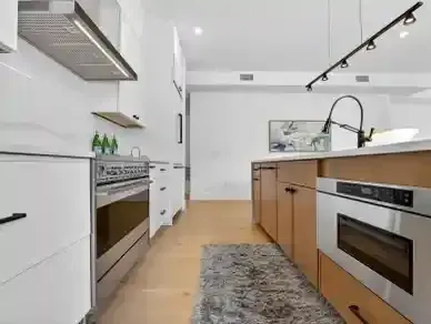 Modern white kitchen with wood island, stainless appliances, and a patterned runner rug