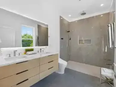 Modern bathroom with double vanity, large mirror, and glass-enclosed shower in neutral tones