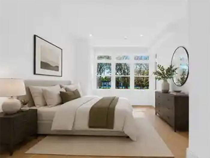 Bright modern bedroom with a large bed, beige bedding, wall art, and a dresser near a window.