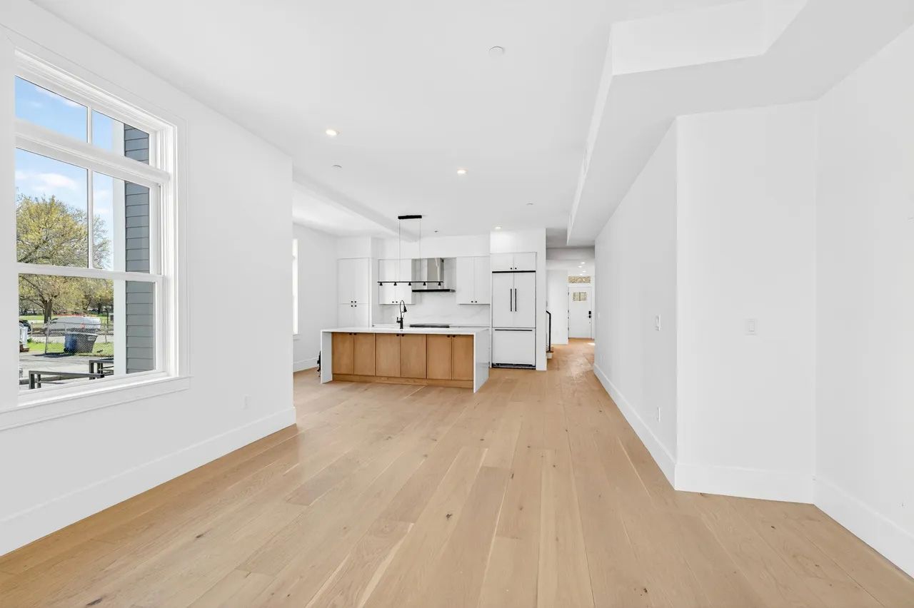Bright white open-plan kitchen and living area with wood floors and large windows