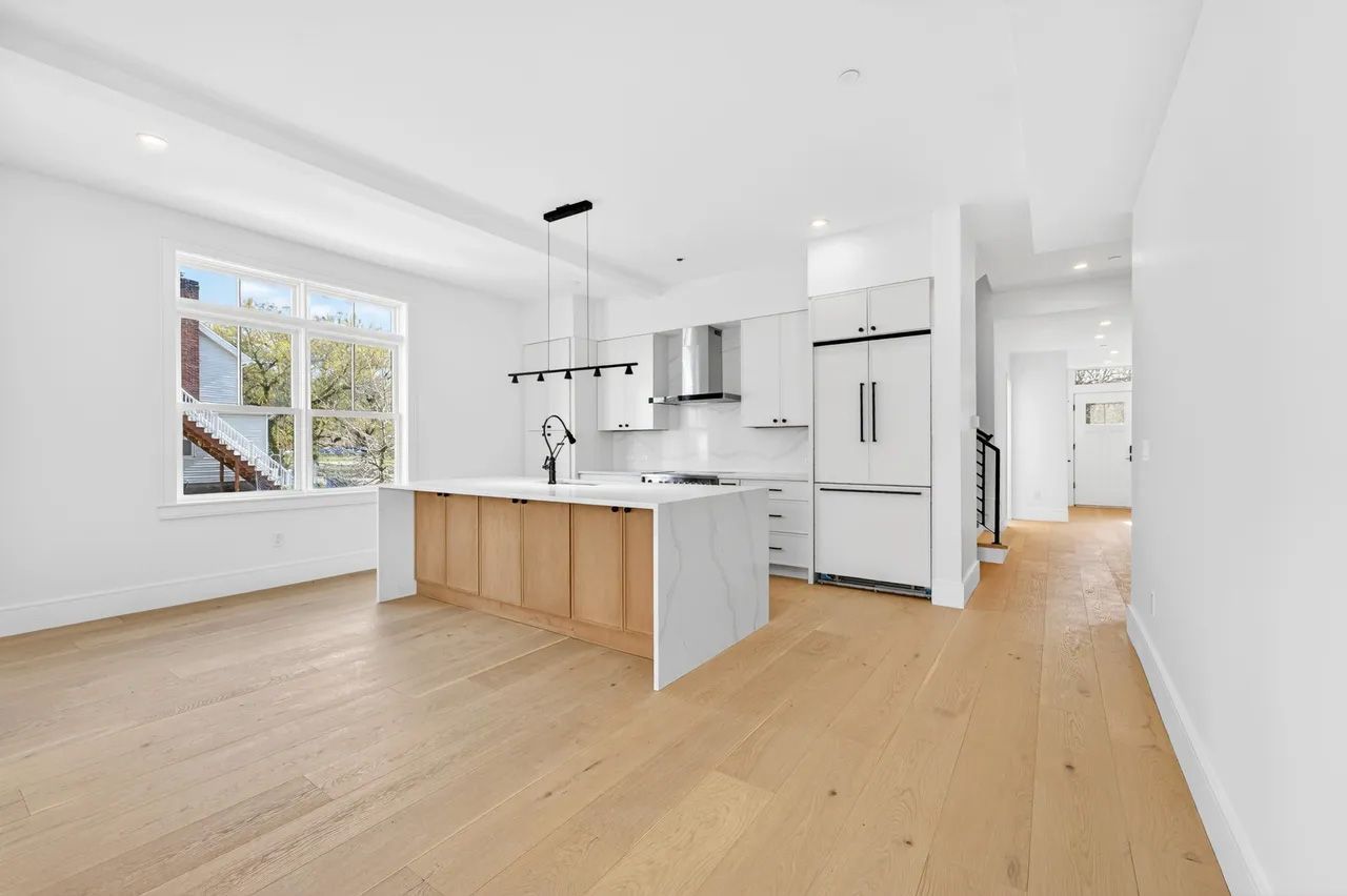 Bright modern kitchen with white cabinets, wood island, light floors, and large windows
