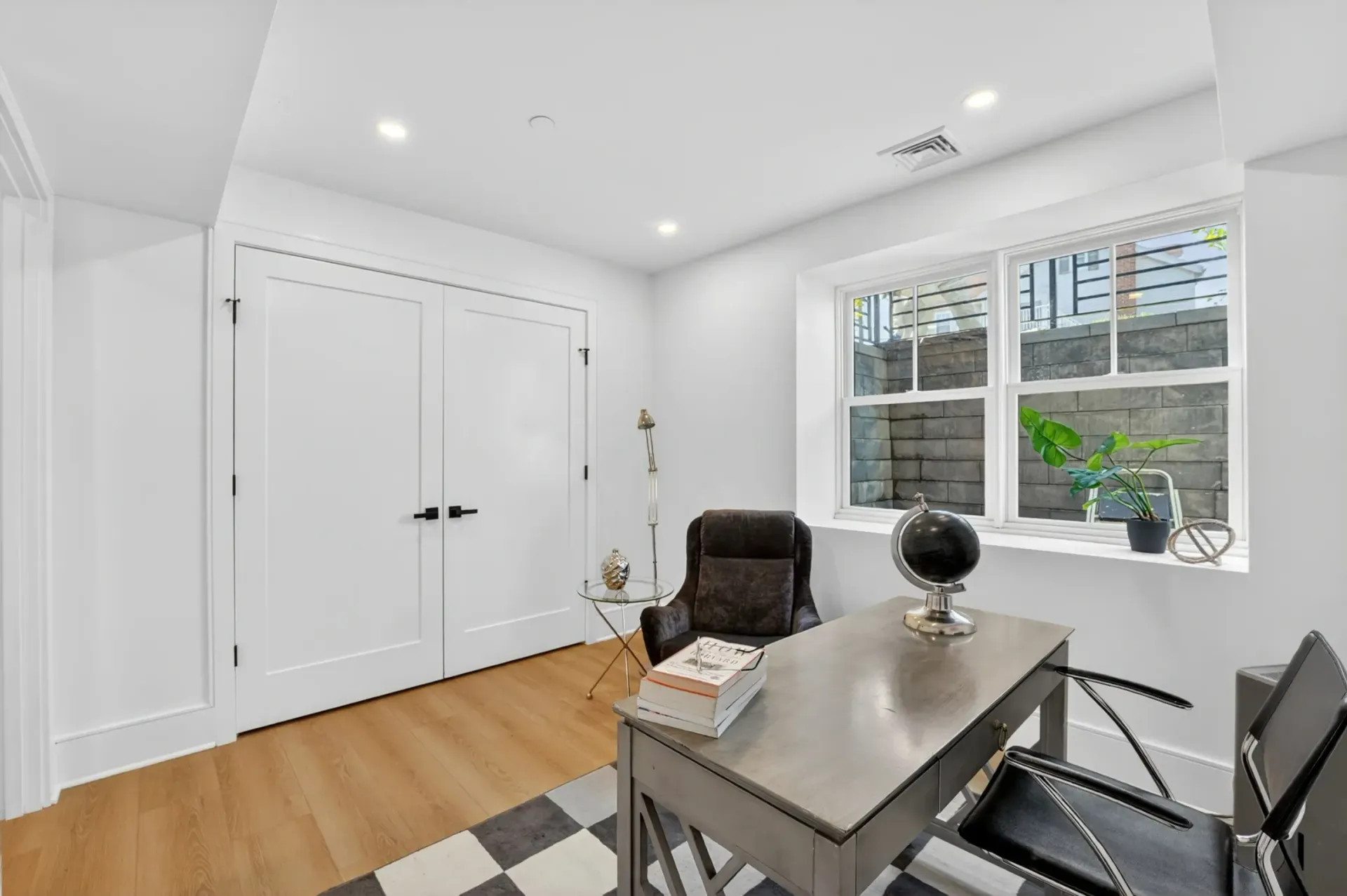 Bright home office with white walls, hardwood floor, desk, chair, and large window