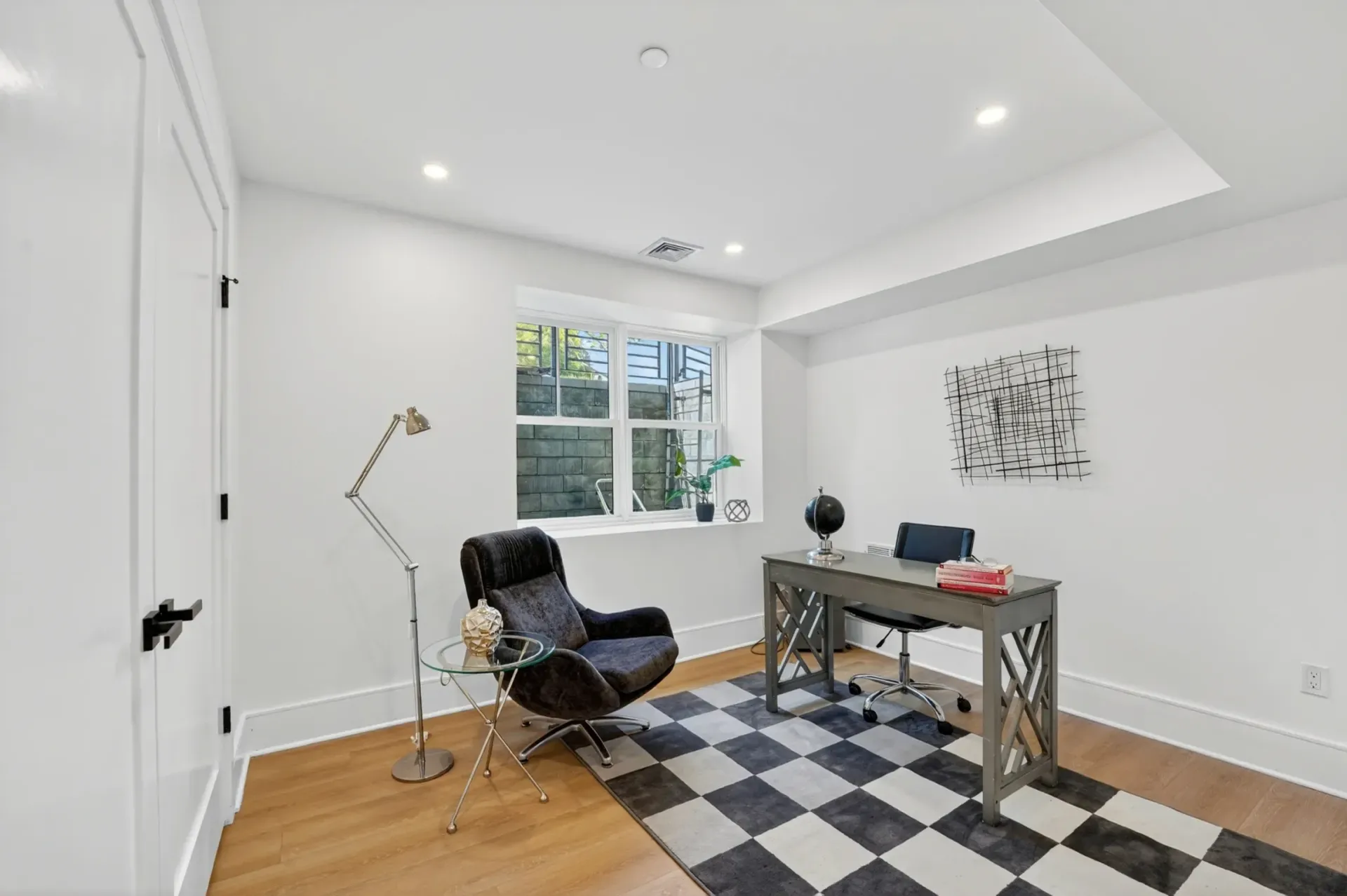 Bright modern home office with desk, chair, floor lamp, window, and black-and-white rug