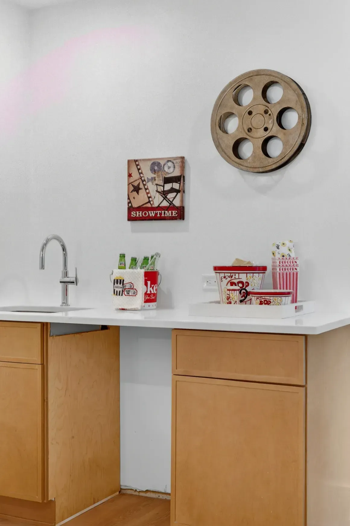 Modern kitchen corner with white countertop, wood cabinets, sink, and wall decor.