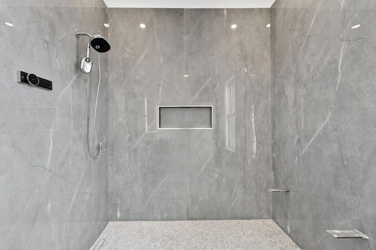 Modern gray-tiled shower with handheld showerhead and built-in niche shelf