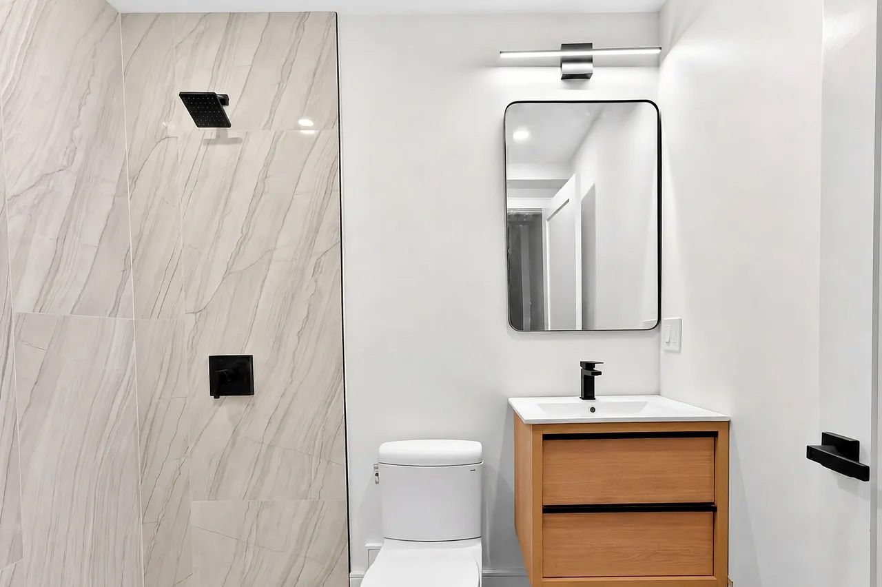 Modern bathroom with shower, toilet, and wooden vanity under a mirror