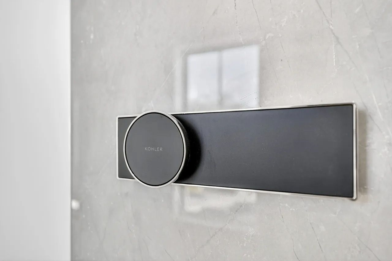Modern black shower control knob on a tiled wall