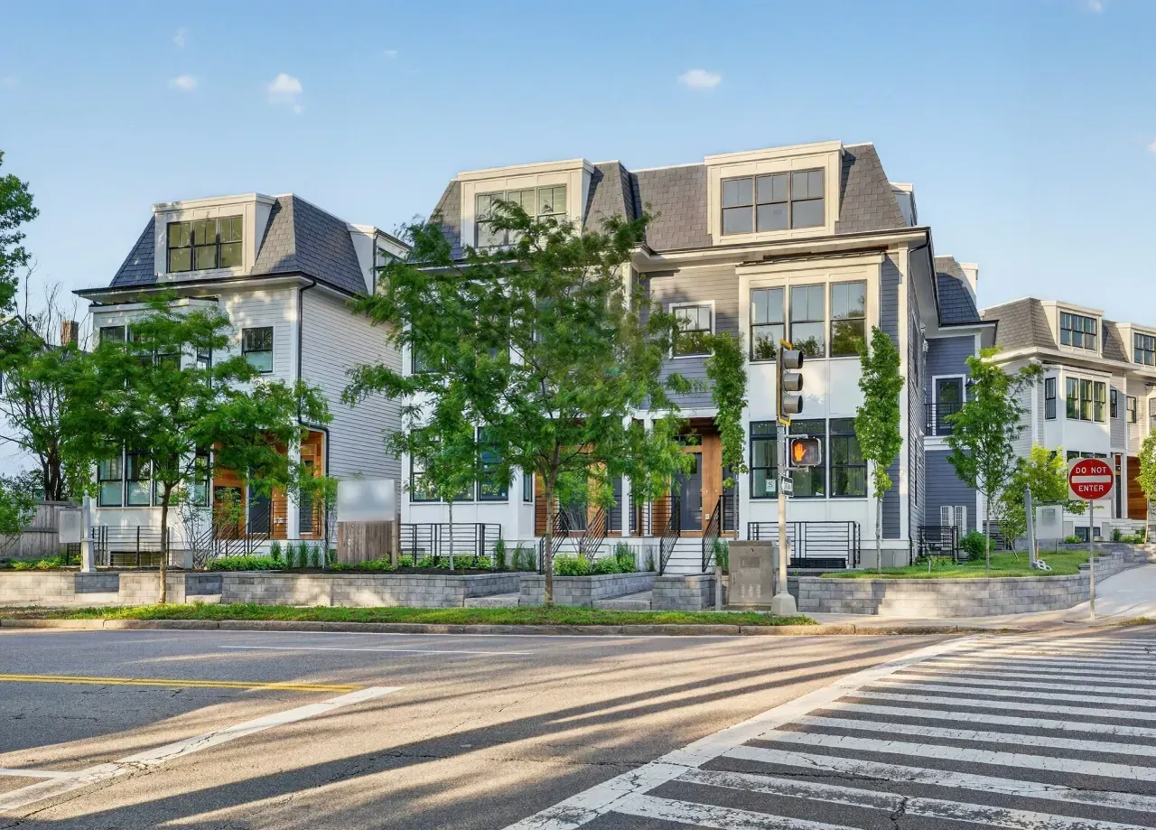 Modern townhouses on a sunny street corner with trees and a crosswalk