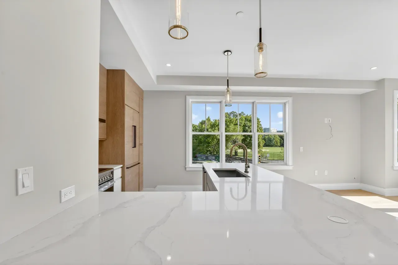 Modern white kitchen and dining area with large window and bright natural light