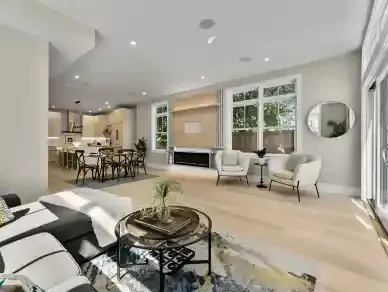 Bright modern open-plan living room with white sofas, round coffee table, and dining area near large windows