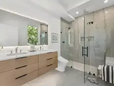 Modern bathroom with double vanity, large mirror, glass shower, and white tile walls