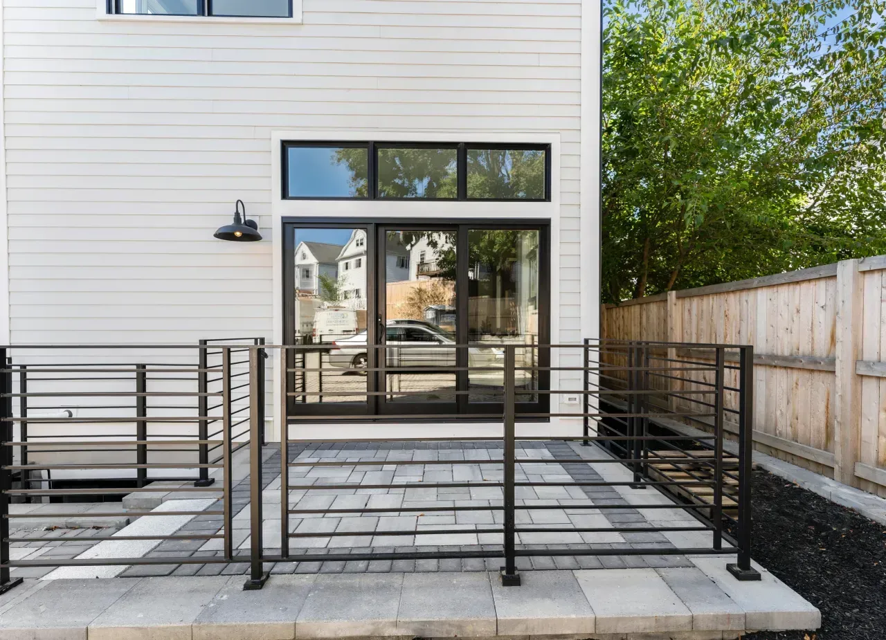 Exterior patio with black railings and a sliding glass door on a white house