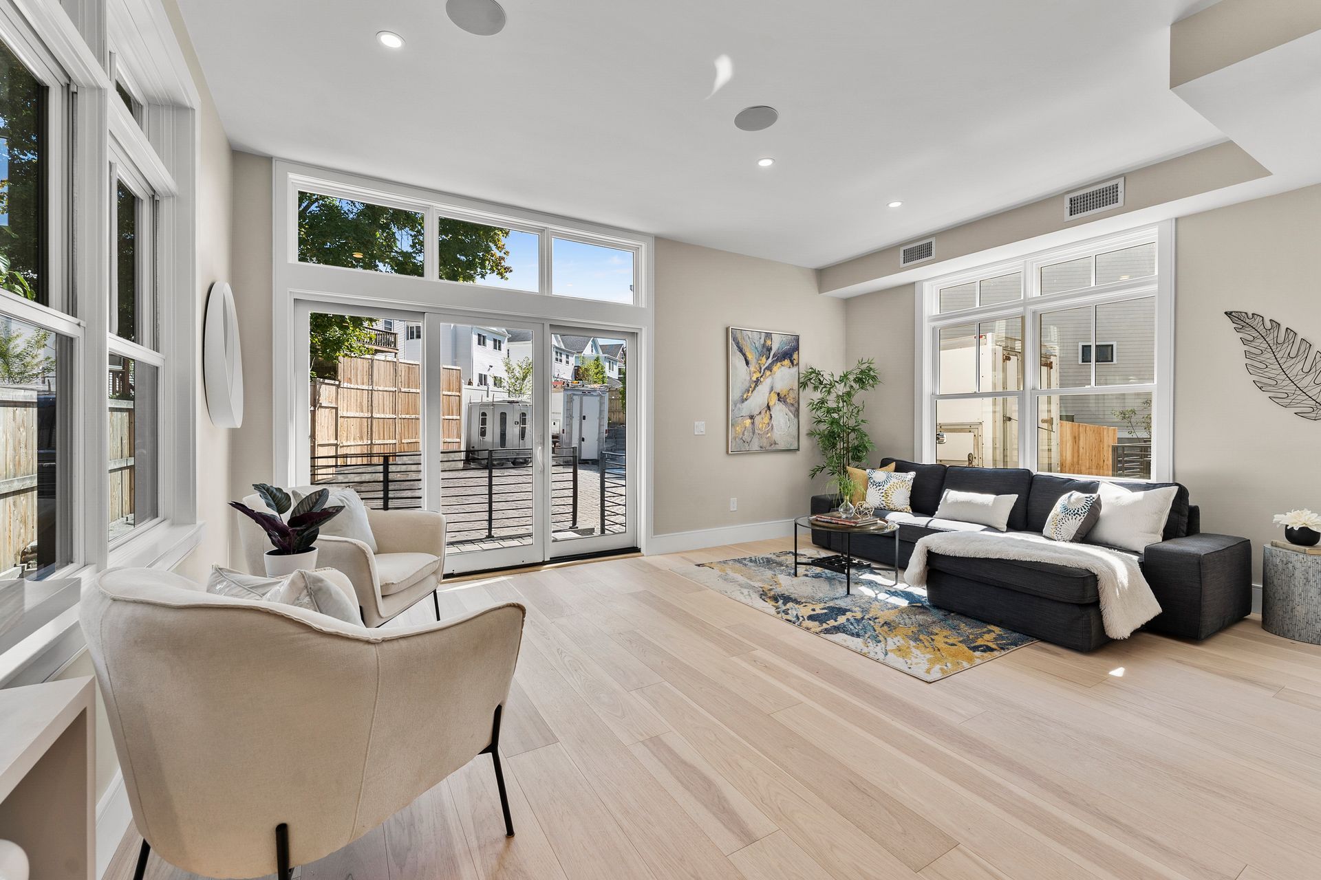 Bright living room with light wood floors, large windows, and modern furniture.